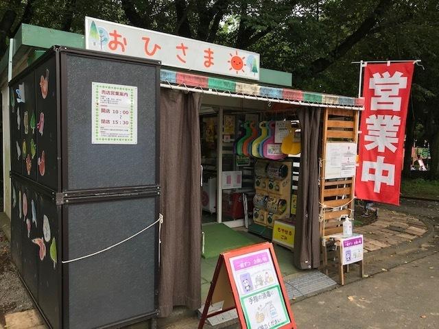 公園内にあるひらがなでおひさまと書かれた看板を掲げ、営業中と書かれた赤いのぼりの立つ売店の外観写真