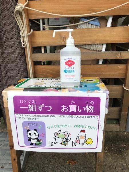 売店前には「一組ずつお買い物」と書かれたポップと消毒液が設置されている写真