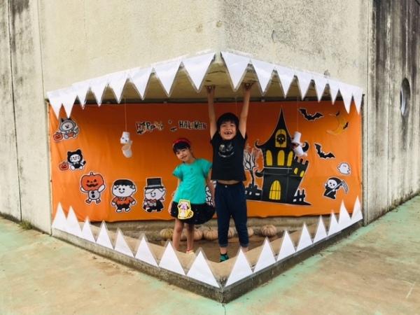 建物に白い三角の紙のようなものをつけオバケの口の中を表現し、その中に入り込む子どもたちの写真