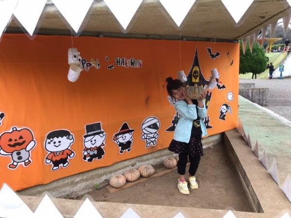 カボチャのオブジェを抱えて笑顔でポーズを撮る女の子の写真