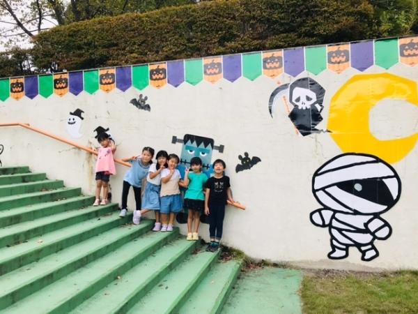 オバケが描かれた階段の壁際に並ぶ子どもたちの写真