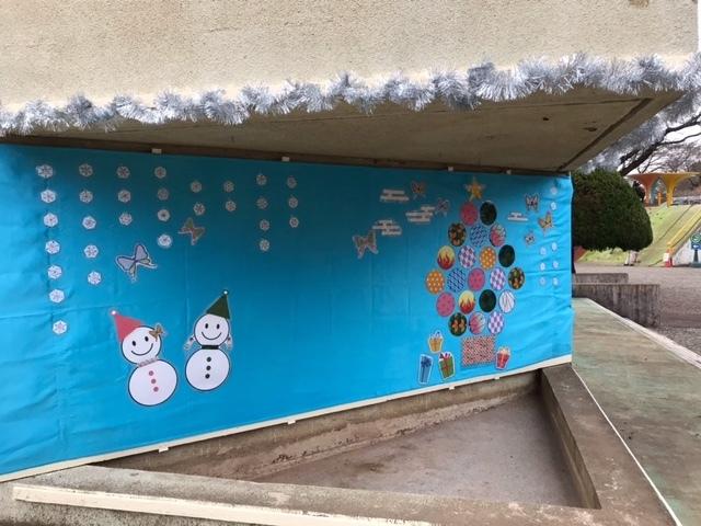 外壁に青色のシートが貼ってあり、シートには雪だるまやリボン、プレゼントの絵などが貼ってある写真
