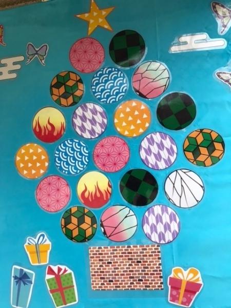 水色のシートにプレゼント形をした絵や蝶々の絵、丸に模様が入っている絵などが貼られている写真