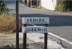 道路の傍にある矢印の書かれた白い看板の写真