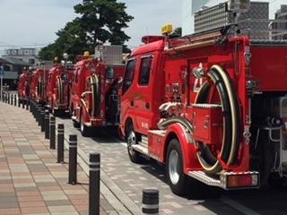 5台ほどの放水車両が縦列に止まっている写真