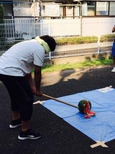 目隠しをした男性が棒を持ってスイカ割りをしている様子の写真