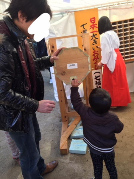 日本一大きなおみくじを小さな子供が引いている写真