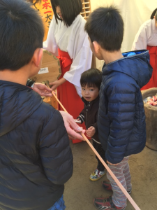 おみくじから出てきている長い棒を子供たちが集まってみている写真