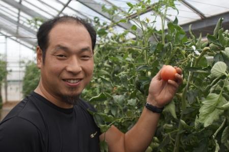 トマトを手に持っているトマト農家の大川さんの写真