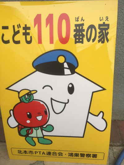 家が警察の帽子をかぶり笑顔で小学生のとまちゃんを見守っているデザインのこども100番の家の看板の写真