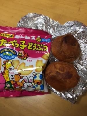 動物のイラストが描かれたピンクのパッケージのお菓子とアルミホイルの上に置かれた茶色の小さな丸いドーナツが置かれた写真