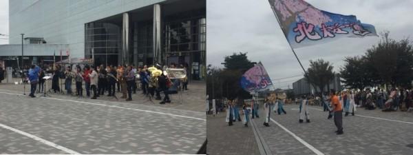 文化センター前で披露されている吹奏楽の演奏と旗を持ちながらよさこいを踊る人々の写真