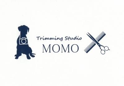コームやカットバサミ、首からカメラを下げたわんちゃんのイラストが書かれた、トリミングスタジオMOMOのロゴマーク