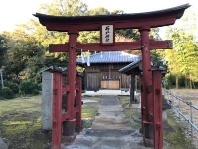 手前に小さな赤い鳥居があり奥に石戸神社がある写真