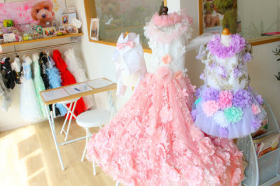 カラフルな花のついたドレスの貸し衣装や奥には赤や白などの色々な種類のの衣装が店内に展示されている様子の写真