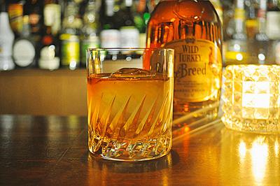カウンターに置かれたグラスに入ったウイスキーをキャンドルが照らしている写真