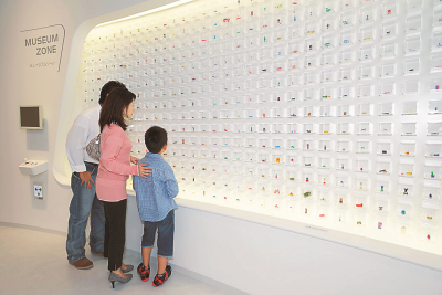 グリコのおもちゃの展示を見ている親子連れの写真