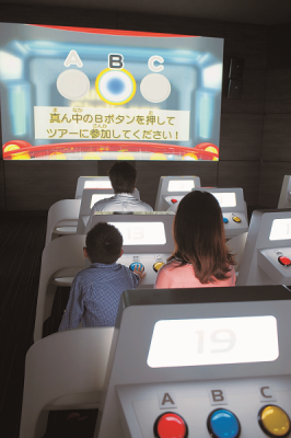 暗闇の中でスクリーンに映し出されるクイズに参加している親子連れの写真