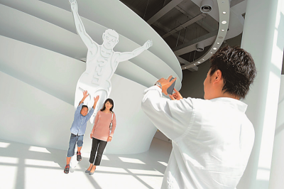 グリコのゴールインマークの前でポーズをしている母子と写真を撮っている父親の写真
