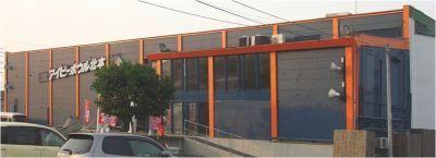 3代の車と横長でオレンジ色の鉄柱がついた建物の外観の写真