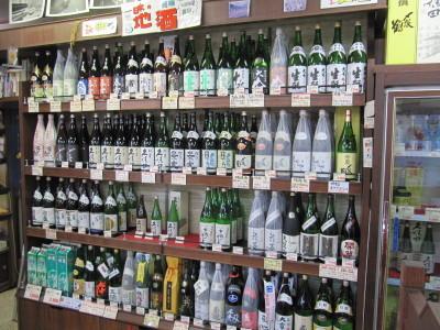 日本酒が4段の棚にずらりと並んでいるくわな屋店内の写真
