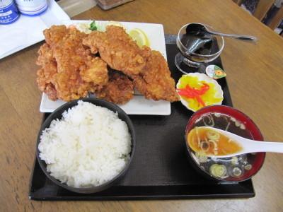 黒いお盆の上に、白いご飯とスープ、白いお皿からはみ出た大きな唐揚げ、デザートのコーヒーゼリー、お漬物がのった唐揚げ定食の写真