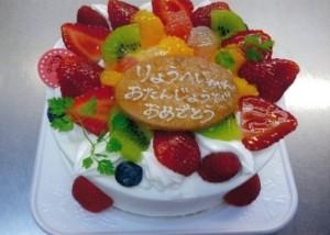 ホールケーキにフルーツがトッピングされた生クリームのデコレーションケーキの写真