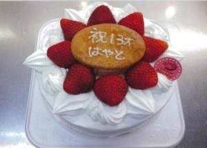 イチゴと誕生日祝いのプレートがのったホールケーキの写真