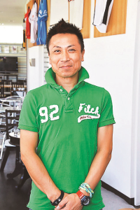 緑のポロシャツを着たのんすた店長の斎藤さんの写真