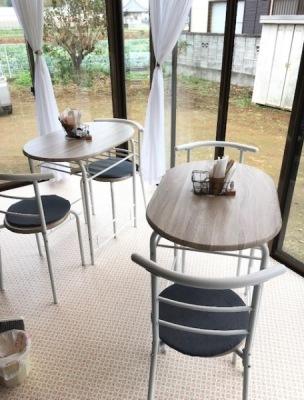 テラスエリアでは、大きめの窓から外の景色を眺めることができ、白い床に2脚ずつセットされた2つのテーブルの店内写真