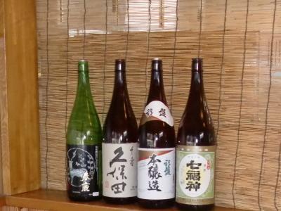 日本酒の緑色の一升瓶1本と茶色の一升瓶3本が並んでいる写真