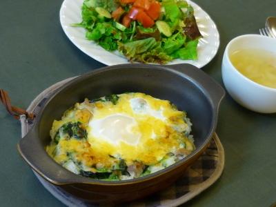 卵がのったドリアと白いお皿にレタスとトマトのサラダとスープがセットになった料理の写真