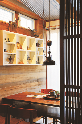 壁に棚がありアンティークの小物が飾られ、木製のテーブルと椅子が置かれたやいち店内の写真