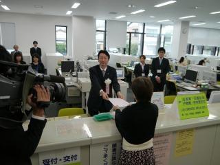 （写真）市長ら市民課窓口にて住民票を受取る