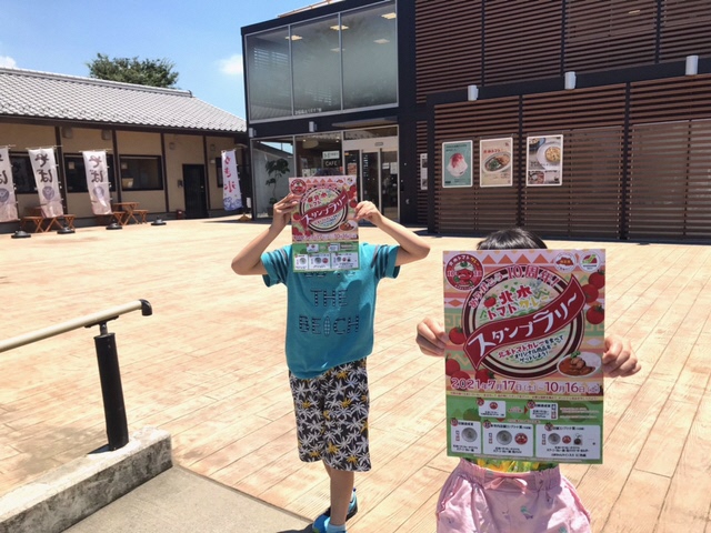 顔の前にスタンプラリー―のチラシを掲げた男の子と女の子