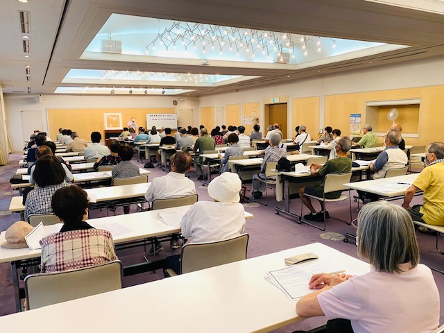 会場の長机に２人づつ受講者が着席している様子