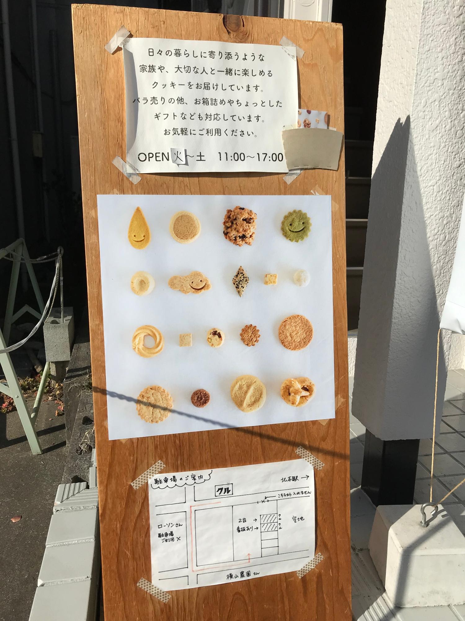 営業時間、クッキーの写真、駐車場案内が張られた看板