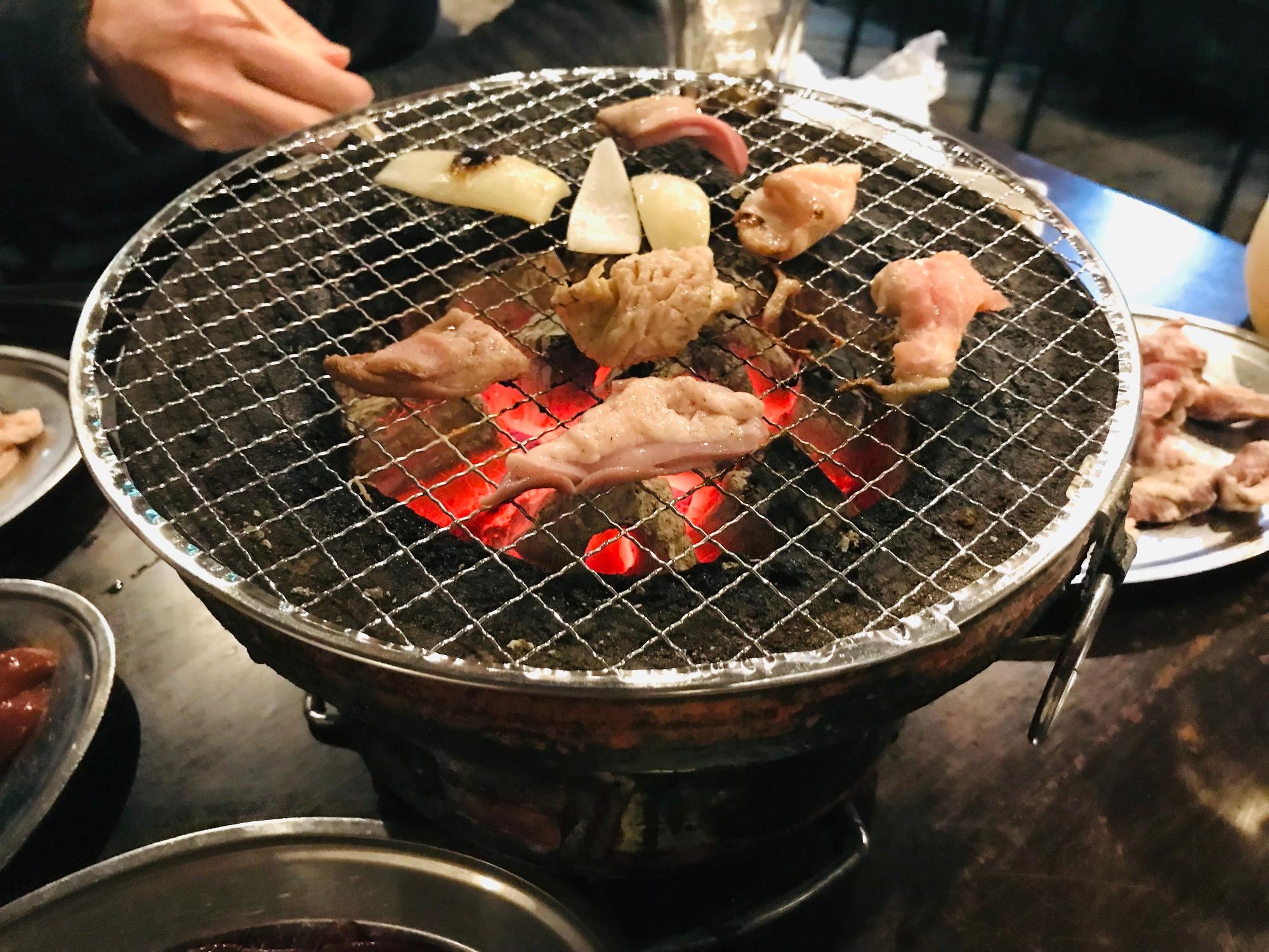 七輪で肉と玉ねぎを焼いている様子