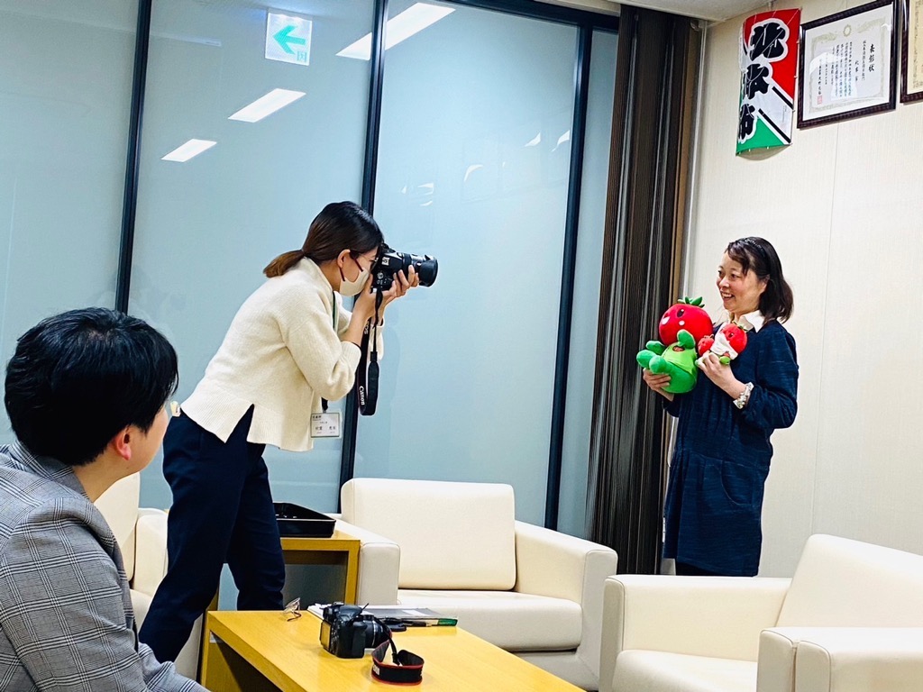 広報担当者が市民リポーターの個別写真を撮影している様子の写真