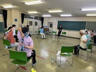 椅子を円形に並べてタオルを使ったストレッチをする参加者の様子