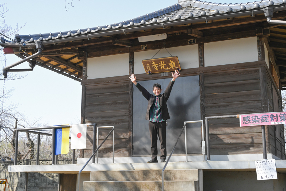 東光寺の本堂前に立つ迫田さんの写真