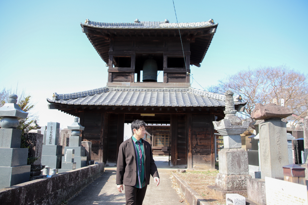 阿弥陀堂の前を歩く迫田さんの写真