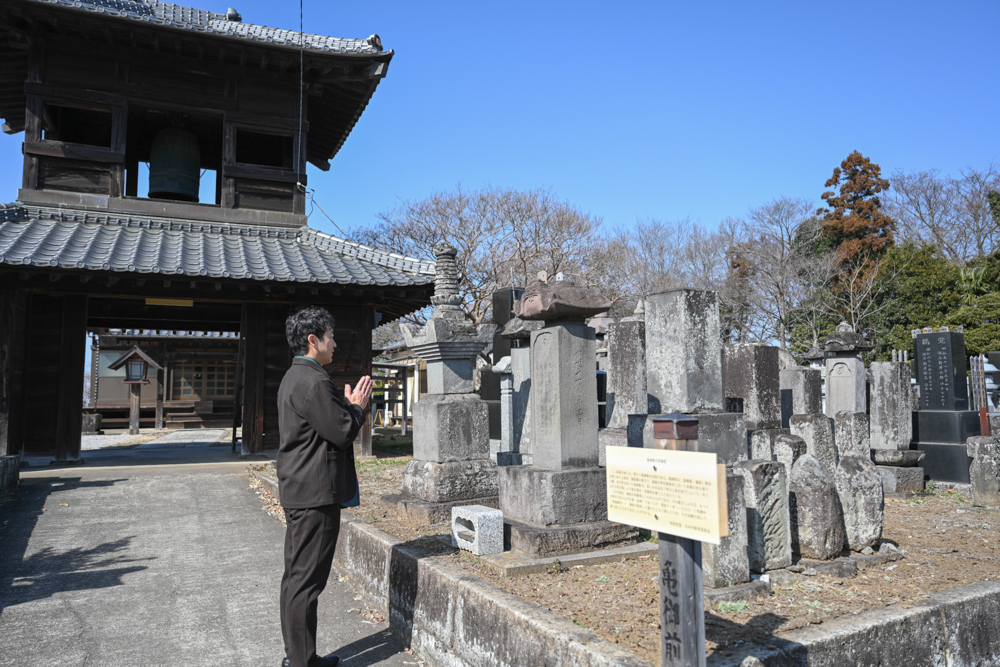 亀御前の碑に手を合わせる迫田さんの写真