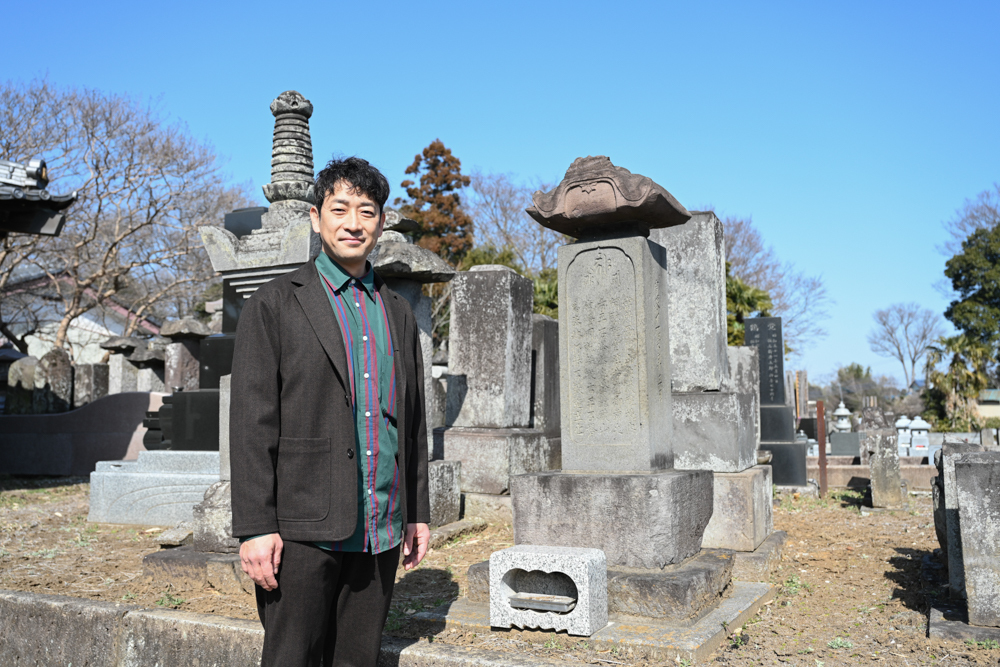 亀御前の碑と並んで立つ迫田さん