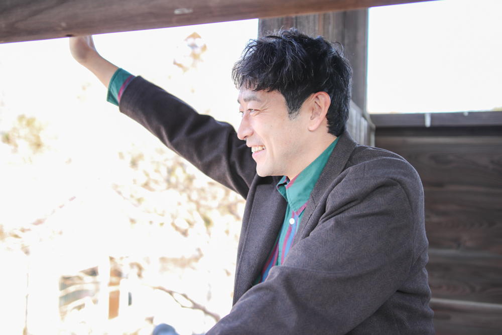 鐘つき堂から手を振る迫田さんの写真