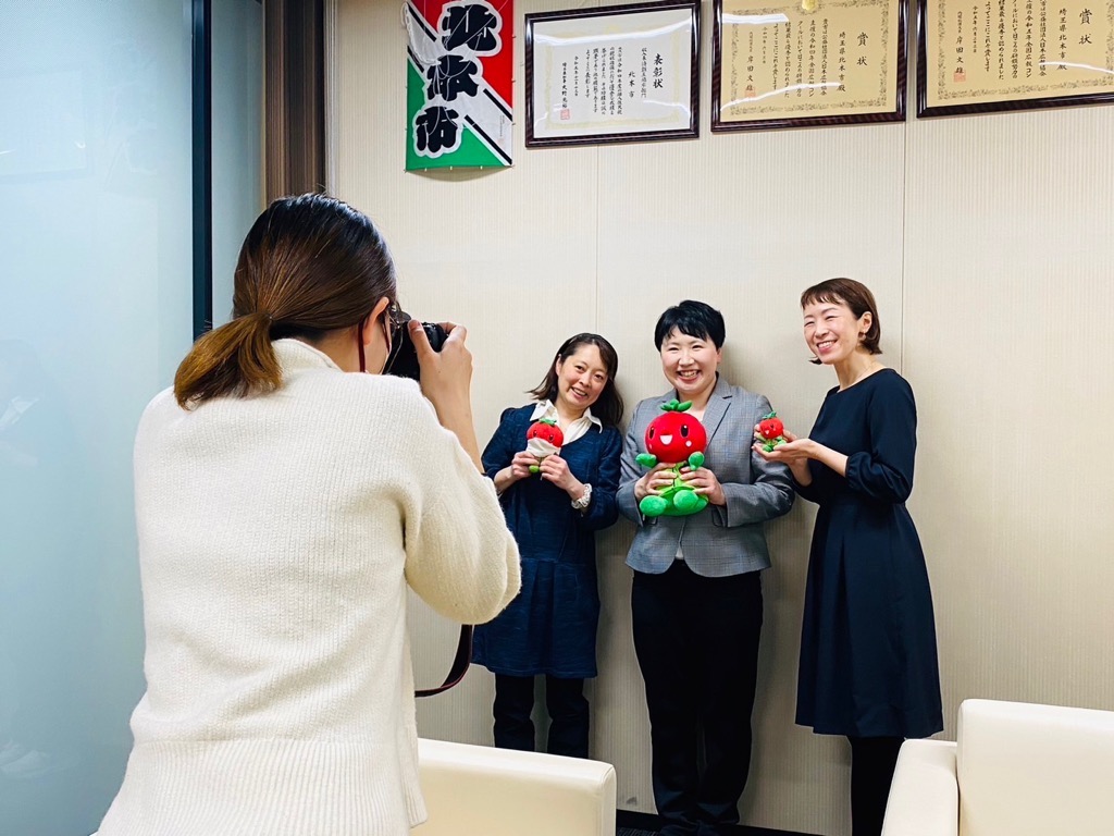 広報担当者が市民リポーターの集合写真を撮影している様子の写真